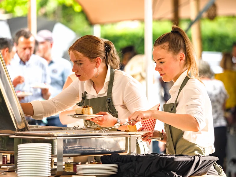 Bedienend personeel schept gerechten op tijdens een buffet bij een evenement