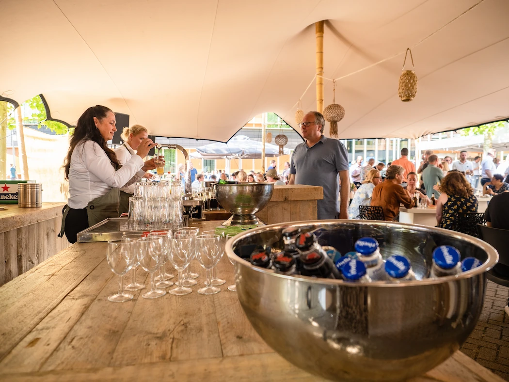 Een serveerster schenkt drankjes in tijdens een levendig buitenevenement