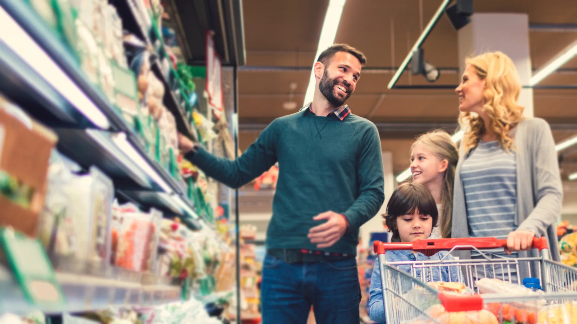 Een man en een vrouw doen boodschappen in de winkel met hun kinderen.