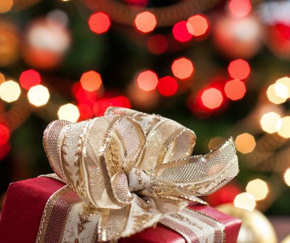 kerstcadeau in rood papier en op de achtergrond kerstlampjes in rood en goud