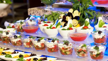 Salades Een salade buffet gevuld met verschillende soorten salades. De salades worden gepresenteerd in glaasjes en bevatten tomaat, komkommer en olijf.