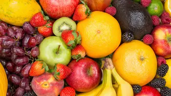 Vers fruit (2) Een schaal met vers fruit zoals blauwe druiven, sinaasappels, groene kiwi's, gele bananen, aardbeien en perzikken.