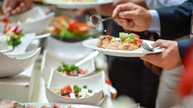 bedrijfscatering Flevoland Een serveerster biedt luxe hapjes aan op een dienblad aan een groep gasten in avondkleding. Gezellig netwerkevenement